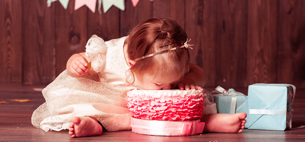 Malé dievčatko sedí pri torte a oslavuje